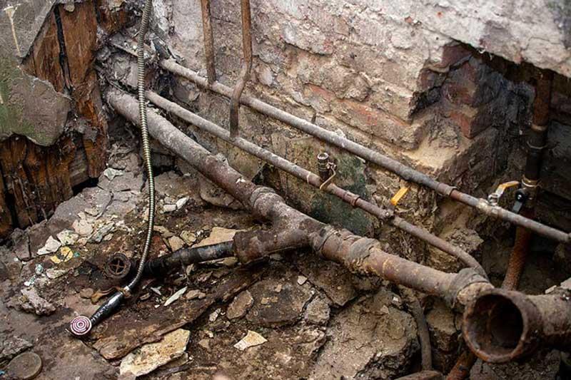 Plumber fixing damaged sewer pipe